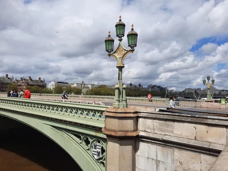 An ornate green lamp standard on Westminster Bridge beside the river.